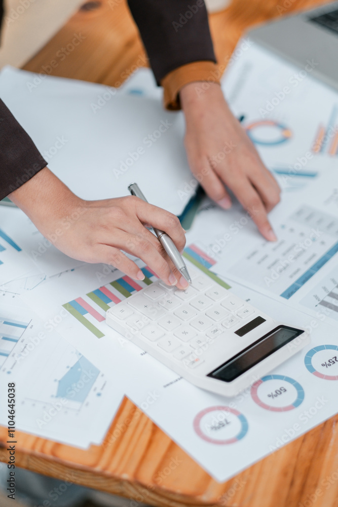 Close-up of hands using a calculator on financial charts, showcasing business analysis and data management. Close-up of hands using a calculator on financial charts, showcasing business analysis and data management.