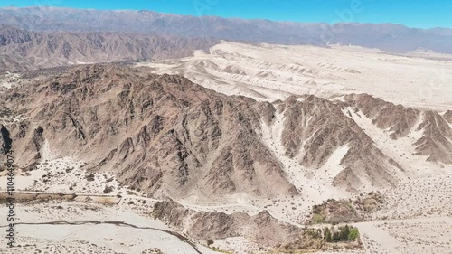 Aerial footage of a barren desert landscape with distant mountain range photo