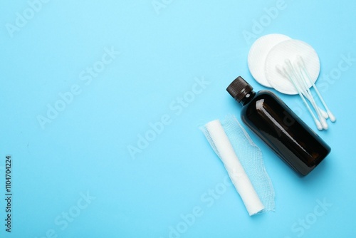 Topical iodine, bandage, cotton pads and swabs on light blue background, flat lay photo