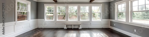 Sunroom with white windows, gray walls, dark wood floors, small window seat, beamed ceiling, home decor style.