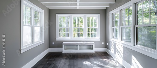 Sunroom with white windows, gray walls, dark wood floors, small window seat, white beamed ceiling, home decor style.
