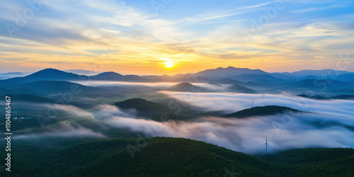 Aerial view of sprawling wind farm at sunrise, capturing serene beauty of mist covered hills and distant mountains