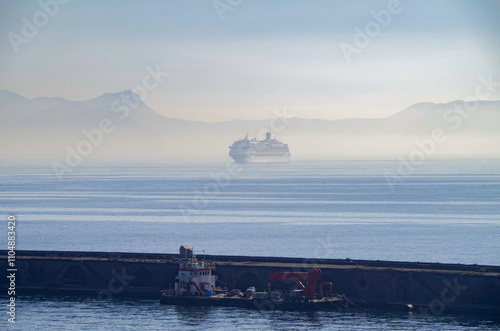 Modern cruiseship cruise ship liner Fascinosa arrival into Napoli Naples, Italy port during summer Mediterranean cruising early morning sunrise fog bank misty photo