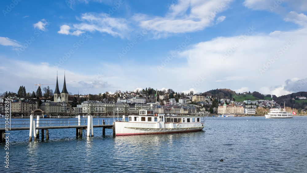 Fototapeta premium Urban landscape of Lucerne, Switzerland, viewed from the shores of Lake Lucerne on a bright and sunny spring day, showcasing the city’s charm and natural beauty.