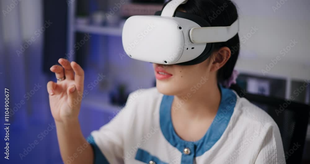 Handheld high angle view shot, Asian freelance woman wearing virtual reality glasses working by touching hands in Metaverse space in home office. Work from home. Handheld high angle view shot, Asian freelance woman wearing virtual reality glasses working by touching hands in Metaverse space in home office. Work from home.
