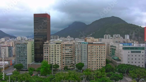 Aerial drone footage of a Rio de Janeiro area, zooming in from the city's modern buildings to the forested mountains.