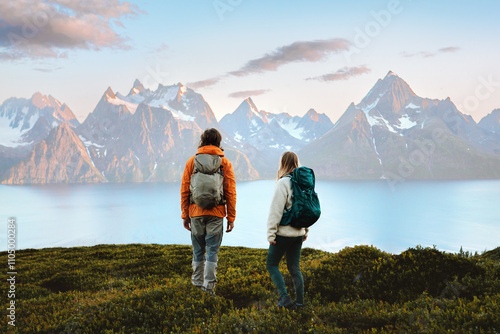 Couple enjoying mountains landscape in Norway friends man and woman hiking with backpack, active vacations healthy lifestyle outdoor family adventurers exploring trails in Lyngen Alps survival trip