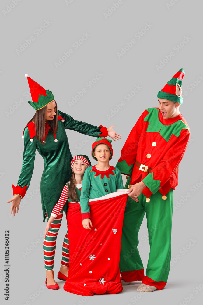 © Pixel-Shot - Happy family in elf's costumes with Santa bag on grey background © Pixel-Shot - Happy family in elf's costumes with Santa bag on grey background