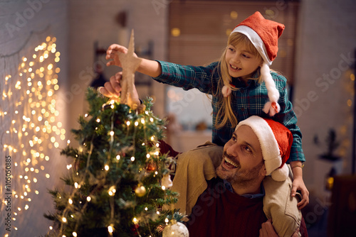 Bilde på lerret Happy father and daughter decorating Christmas tree and putting star on top of it