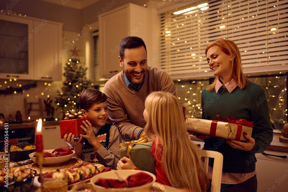 Happy father sharing Christmas presents during family dinner in dining room. Happy father sharing Christmas presents during family dinner in dining room.