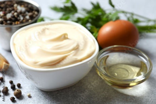 Bowl with mayonnaise and ingredients for cooking on gray background photo