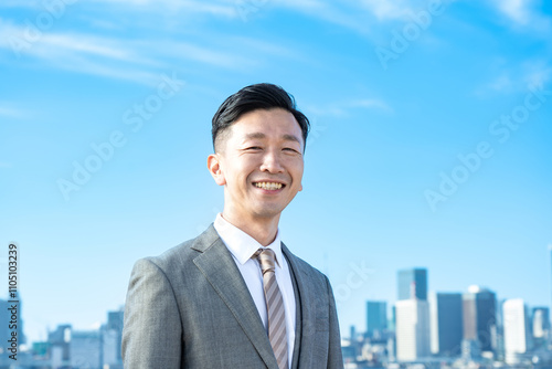 青空とビル群を背景にしたビジネスマンのポートレート