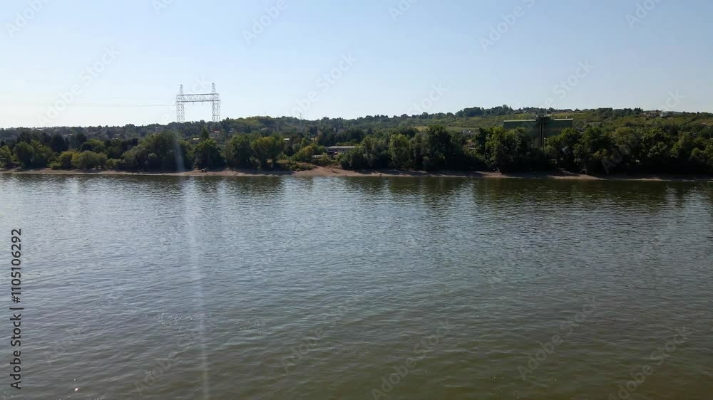 Serene afternoon by the river with clear skies and lush greenery in the background Serene afternoon by the river with clear skies and lush greenery in the background