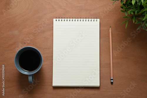 Blank notepad, pencil and a cup of coffee on wooden desk for starting a productive day of writing or planning photo