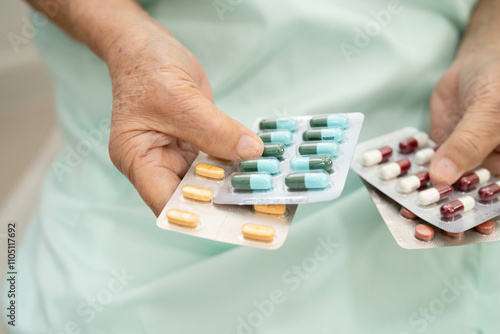 Asian elderly woman holding pill drug in hand, strong healthy medical concept.