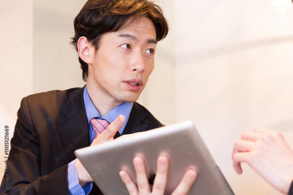 タブレットでコンサルティングをしているスーツ姿の日本人男性 タブレットでコンサルティングをしているスーツ姿の日本人男性