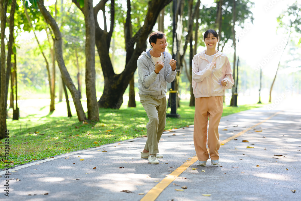 Happy an older man and his daughter enjoying their exercise routine, jogging together through a park path Happy an older man and his daughter enjoying their exercise routine, jogging together through a park path