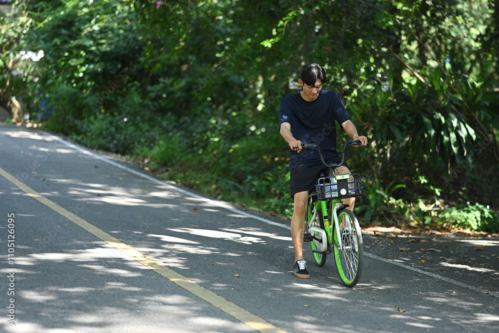 Happy asian man riding his bike through along the scenic path enjoying the outdoor exercise Happy asian man riding his bike through along the scenic path enjoying the outdoor exercise