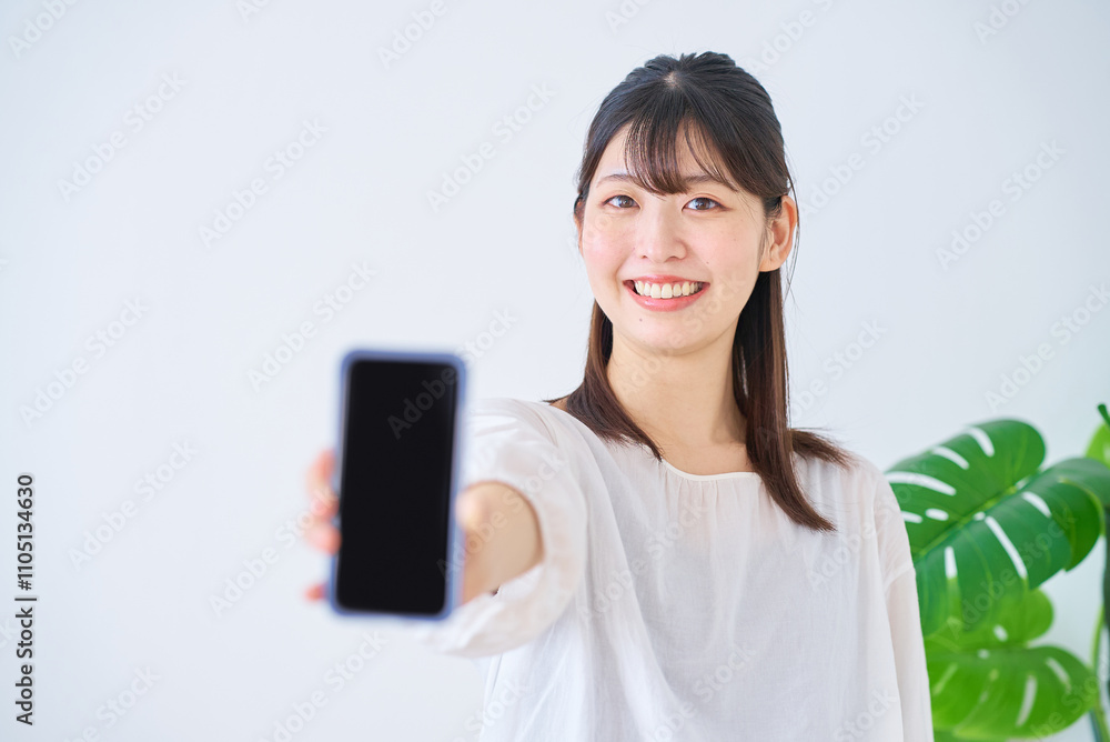 スマートフォンの画面を見せる若い女性