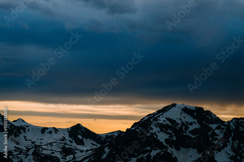 A small plane flies between two mountains at sunset. photo