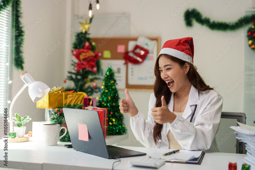 Doctor working at desk on Christmas Eve wearing a festive Santa hat She uses a laptop to communicate with work. Have fun chatting online happy surprised Excited during the holiday season. Doctor working at desk on Christmas Eve wearing a festive Santa hat She uses a laptop to communicate with work. Have fun chatting online happy surprised Excited during the holiday season.