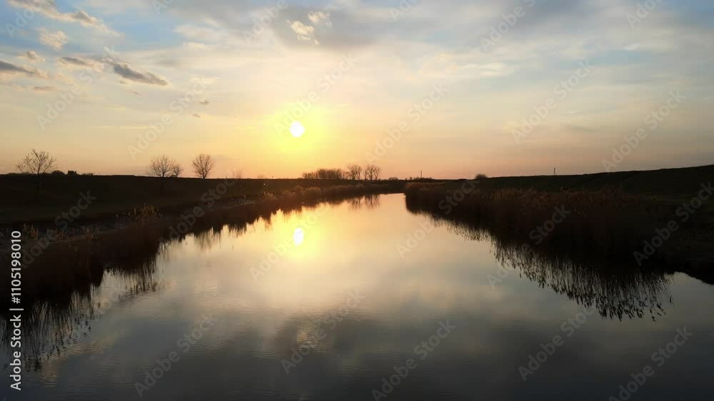 Sunset reflections over calm water in a serene landscape during evening hours Sunset reflections over calm water in a serene landscape during evening hours