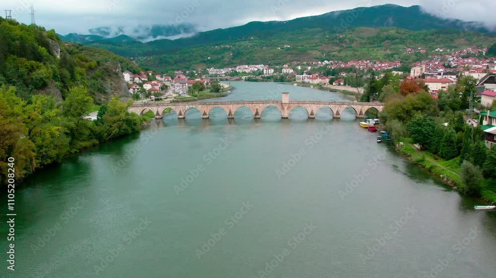 Exploring the scenic landscape of a historic bridge and river in a picturesque town surrounded by mountains Exploring the scenic landscape of a historic bridge and river in a picturesque town surrounded by mountains