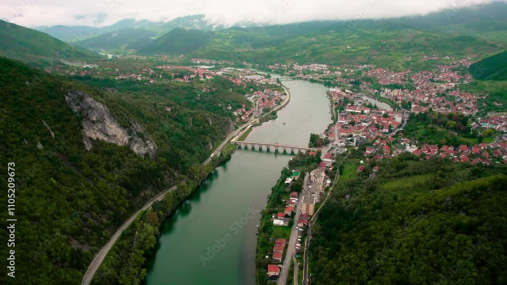 Stunning aerial view of a river flowing through a scenic valley with a charming town alongside Stunning aerial view of a river flowing through a scenic valley with a charming town alongside