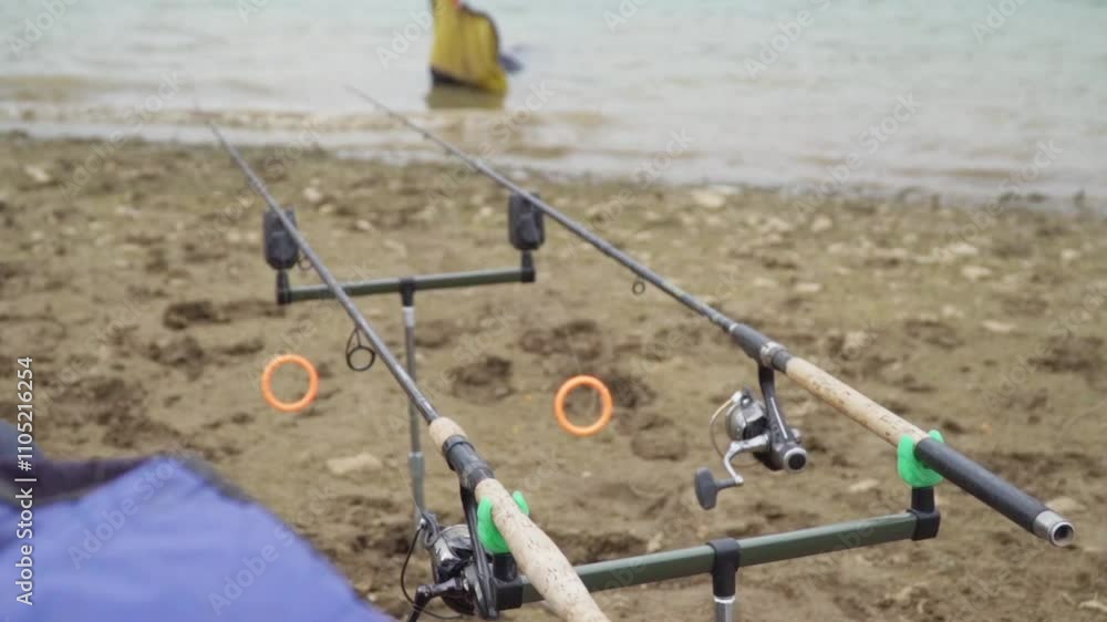 Fishing rods set up on the shore with calm water in the background during a peaceful afternoon Fishing rods set up on the shore with calm water in the background during a peaceful afternoon