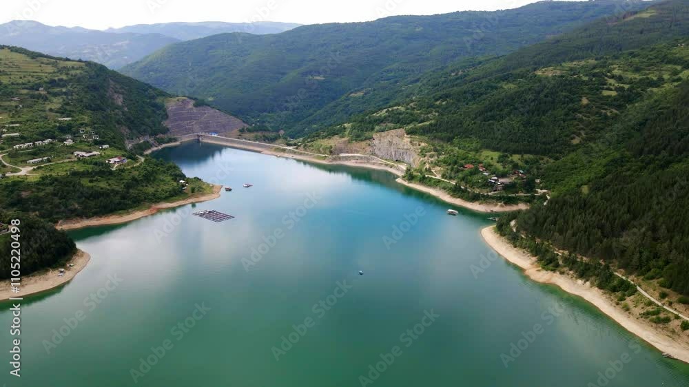Scenic aerial view of a serene lake surrounded by lush mountains during a sunny day Scenic aerial view of a serene lake surrounded by lush mountains during a sunny day