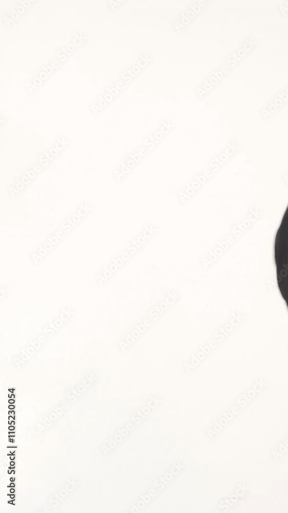 a showman in a stylish black suit with a bow tie is posing and walks out of sight on the white background. Vertical video a showman in a stylish black suit with a bow tie is posing and walks out of sight on the white background. Vertical video