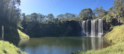 Spectacular Waterfall cascading into a serene lake, surrounded by lush greenery under a clear blue sky. A picturesque natural landscape, perfect for relaxation and adventure.