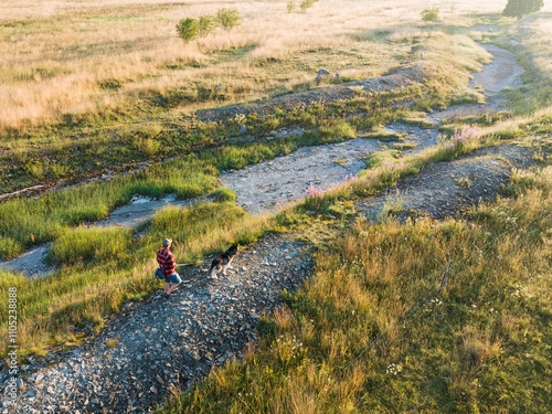 A man and a Siberian husky dog ​​walk near the bed of a dry river on a summer day. photo