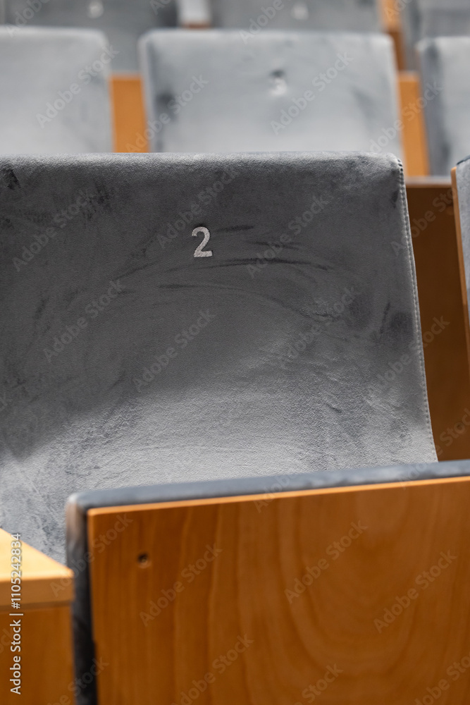 Rows of empty seats in a cinema hall, front side of the seats with numbers. Close-up with shallow depth of field