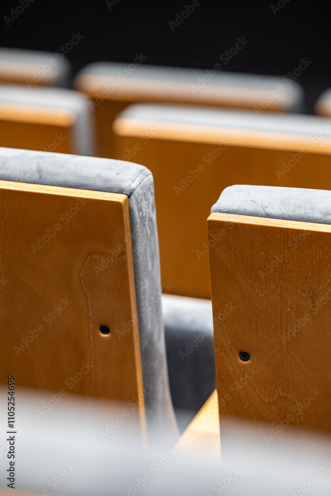 Rows of empty seats in a cinema hall - close-up with shallow depth of field. View of the back part made of light plywood.