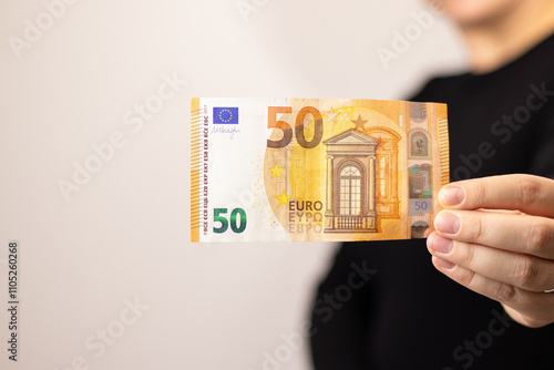 Close up of a woman holding one fifty euro bill, grey background  photo