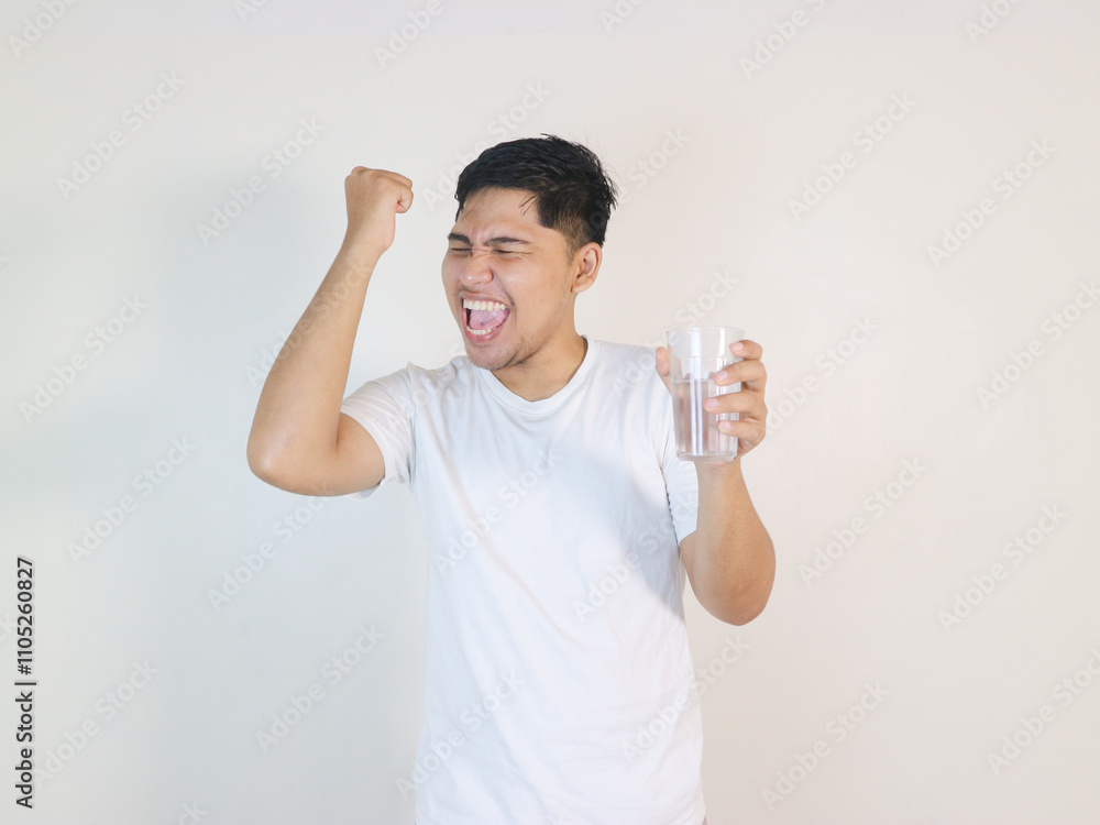 Asian sporty handsome and cheerful young man with a glass of drinking water, isolated on background Asian sporty handsome and cheerful young man with a glass of drinking water, isolated on background