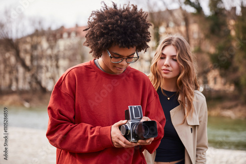 Young mixed race couple taking pictures with a vintage analog camera. Munich, Germany photo