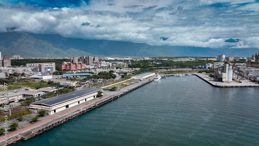 Scenic view of Hualien harbor in Taiwan with mountains and modern buildings under a blue sky Scenic view of Hualien harbor in Taiwan with mountains and modern buildings under a blue sky