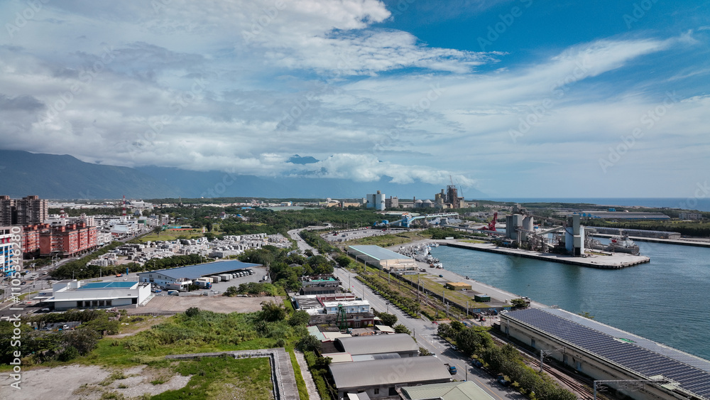 Fototapeta premium Aerial view of Hualien port area with lush greenery and urban landscape under a bright blue sky