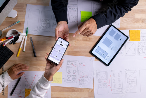 UX UI designers discussing and brainstorming on wireframes for a website and mobile app prototype, in the concept of website and mobile application design concept.