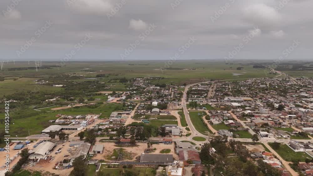 Aerial backwards shot of Chui City in Brazil. Border town to Uruguay with rotating wind turbines in background. Wide shot. Aerial backwards shot of Chui City in Brazil. Border town to Uruguay with rotating wind turbines in background. Wide shot.