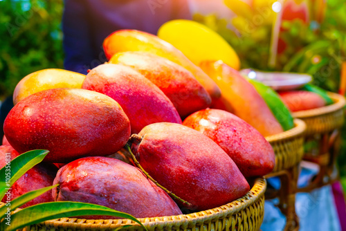 Red large big mango with branches foliage tree saplings neatly laid out on a small fruit stall in tropical fruits market. photo