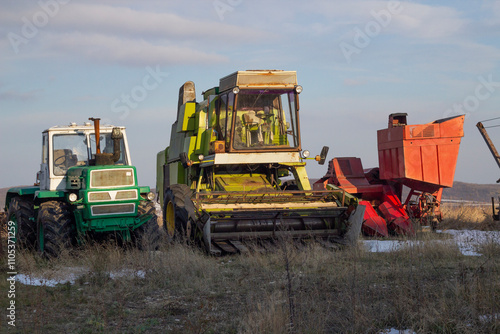 Abandoned farming machinery rests in a field under a cloudy sky during late afternoon hours