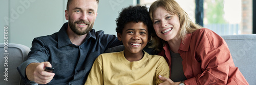 Fotografie Portrait of happy family sitting on comfortable sofa while watching TV together