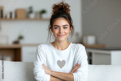 A woman with a casual bun hairstyle, wearing a heart print sweater, sits comfortably in a cozy room, exuding self-contentment and relaxed confidence. photo