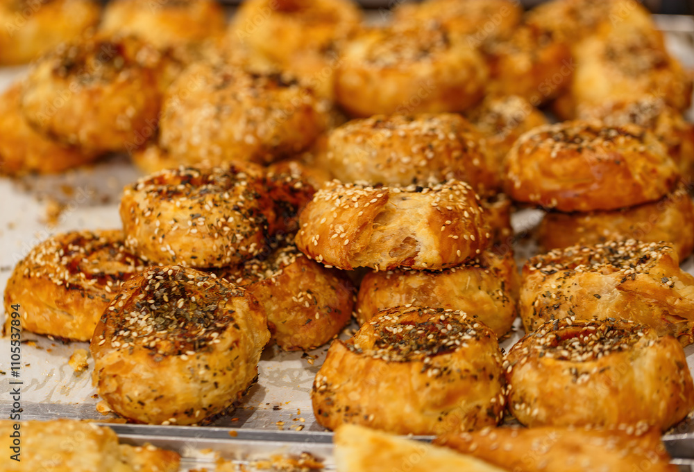 Freshly baked pastries with sesame seeds displayed at a bakery. The brown treats are generously topped with sesame seeds, showcasing their flaky texture. The inviting aroma fills the air Freshly baked pastries with sesame seeds displayed at a bakery. The brown treats are generously topped with sesame seeds, showcasing their flaky texture. The inviting aroma fills the air