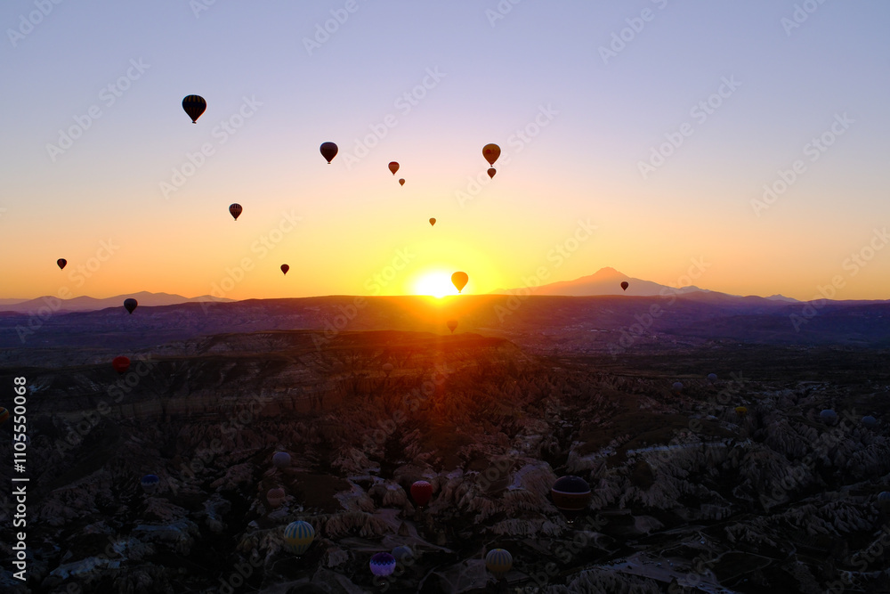 sunrise on horizon with hot air balloons in sky in Cappadocia, Turkey