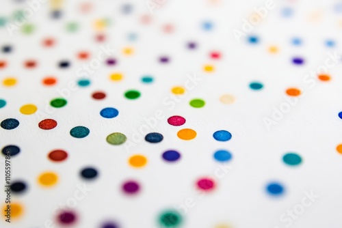 Small, colorful dots scattered randomly across a white surface, creating an energetic and playful abstract composition that draws attention through color diversity.