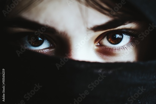 Intense eyes peer out from behind a black fabric, evoking mystery and intrigue, highlighting the concept of concealed identity and enigmatic presence. photo